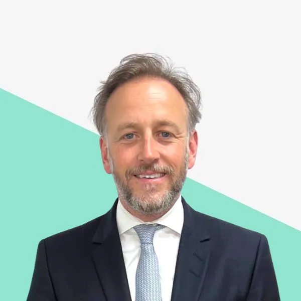 Smiling man in a suit against a light background.