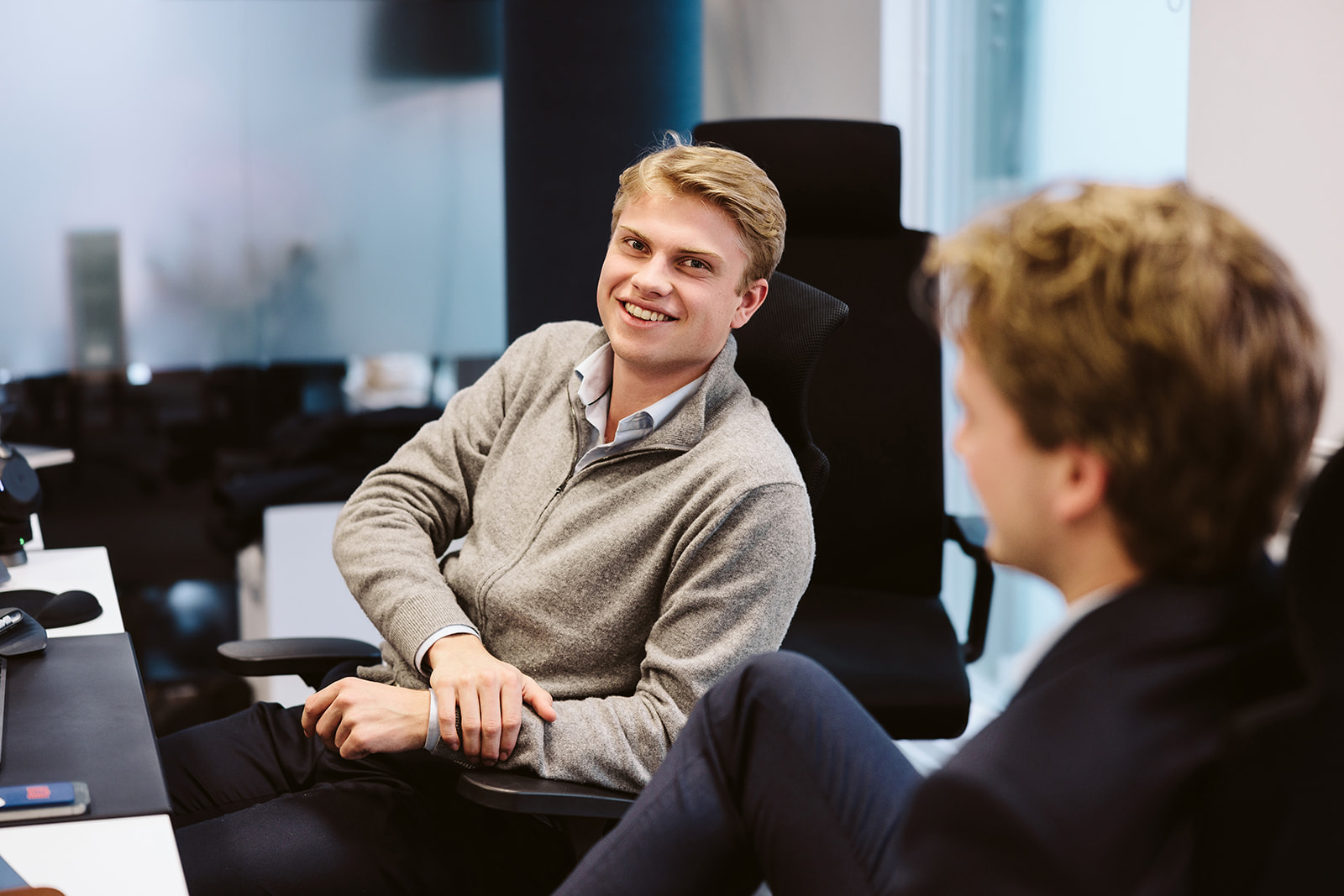 two men sitting at desk, talking