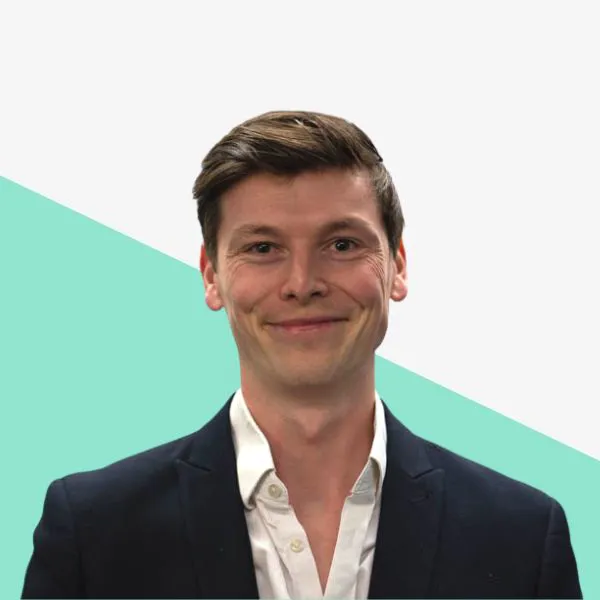 Smiling man in a suit against a light background.