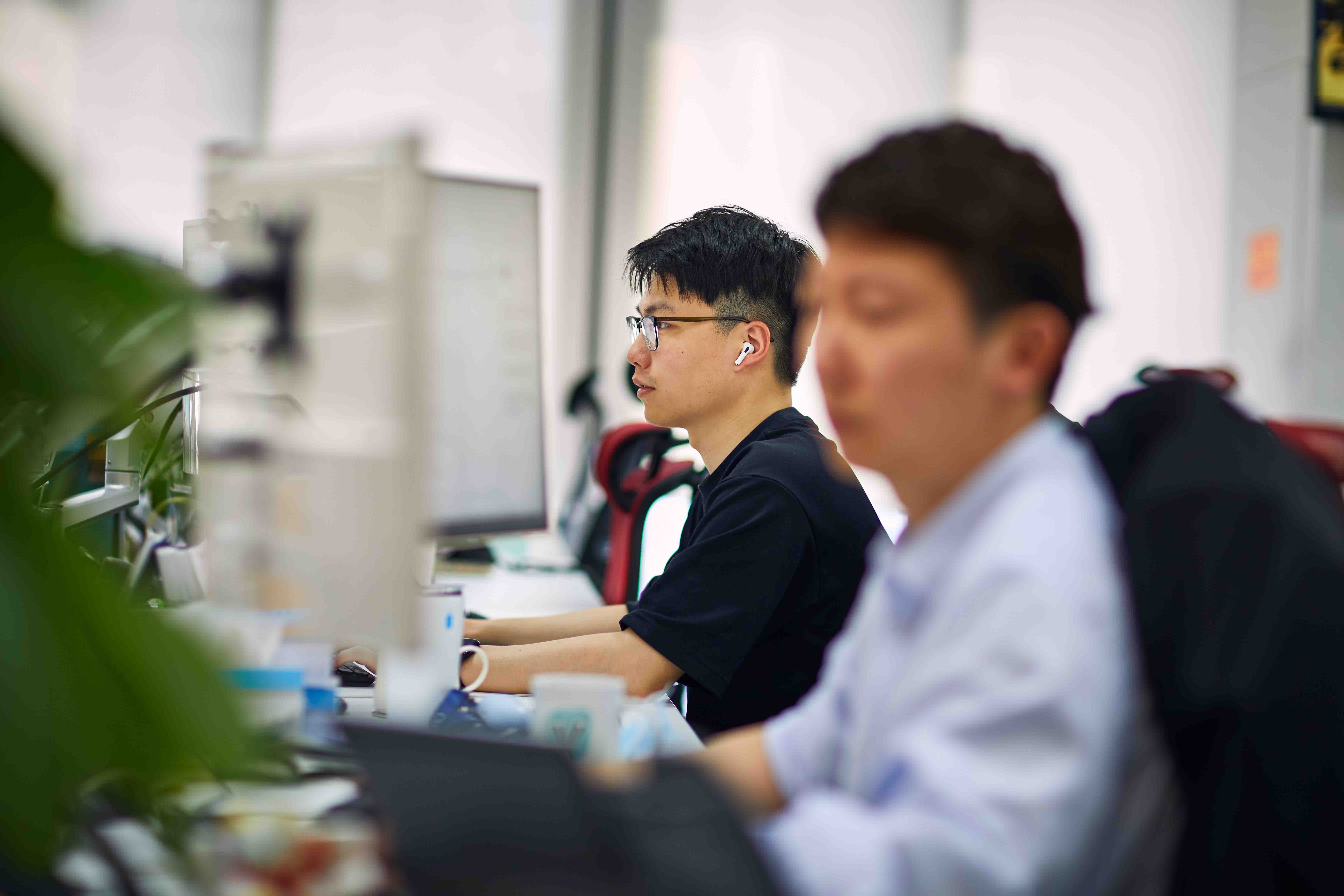 Two people working at desks in an office setting.