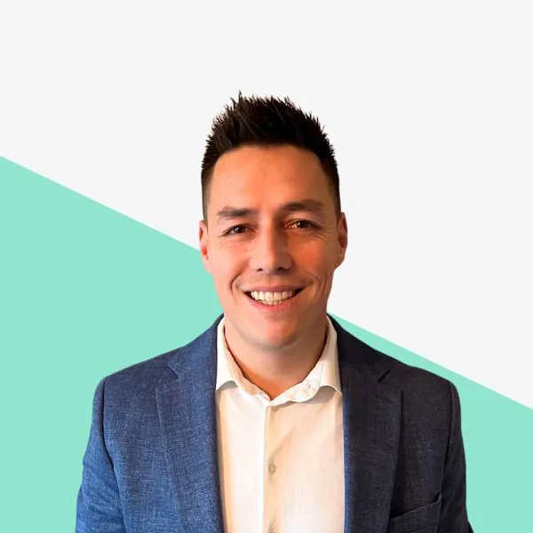 Smiling man wearing a blazer against a light background.