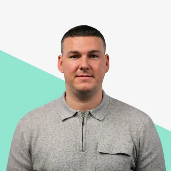 Man in a gray zip-up shirt against a light background.