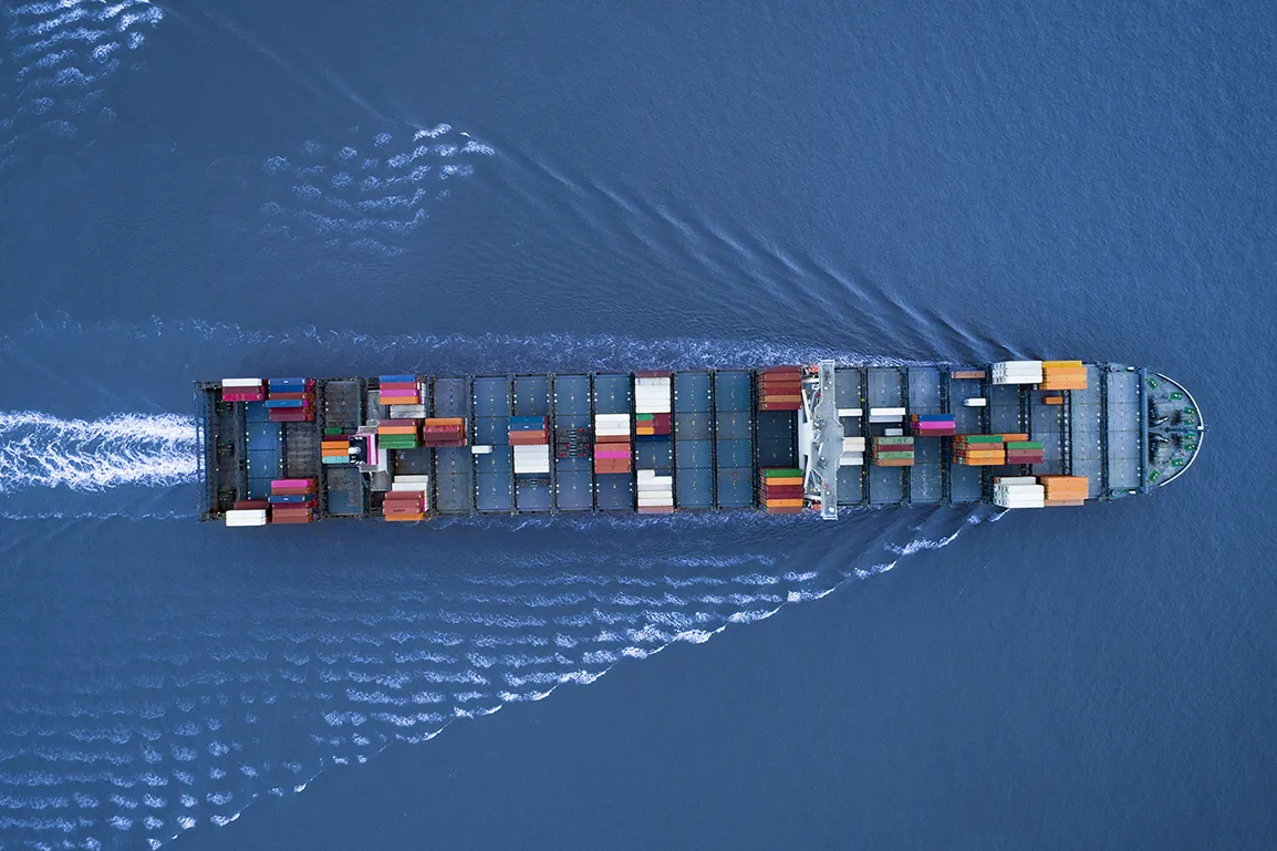 a Large container ship is approaching the port full loaded with containers and cargo, aerial, top down view