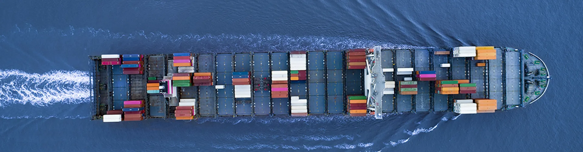 a Large container ship is approaching the port full loaded with containers and cargo, aerial, top down view
