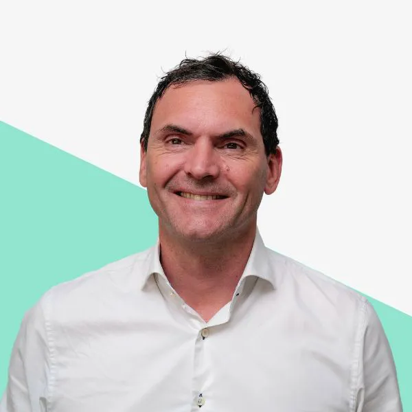 Smiling man in a white shirt against a plain background.