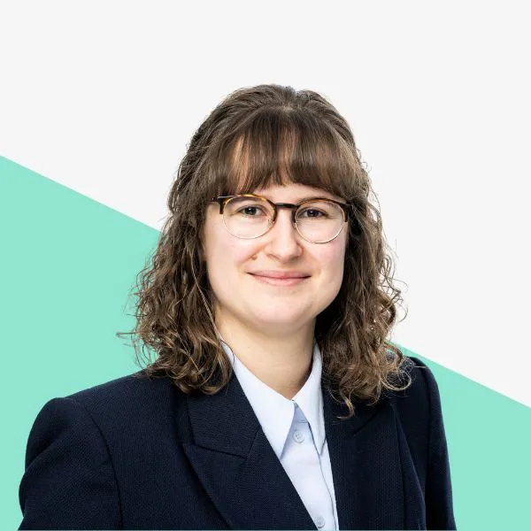 Smiling person with curly hair and glasses.