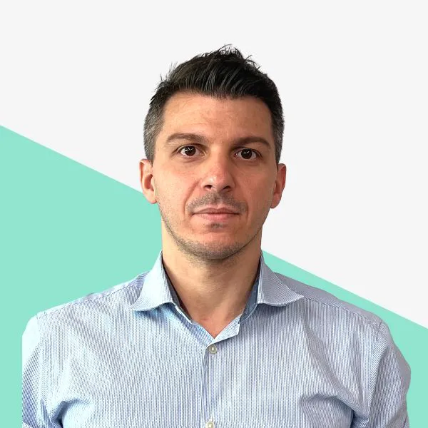 Man in a light blue shirt against a teal background.