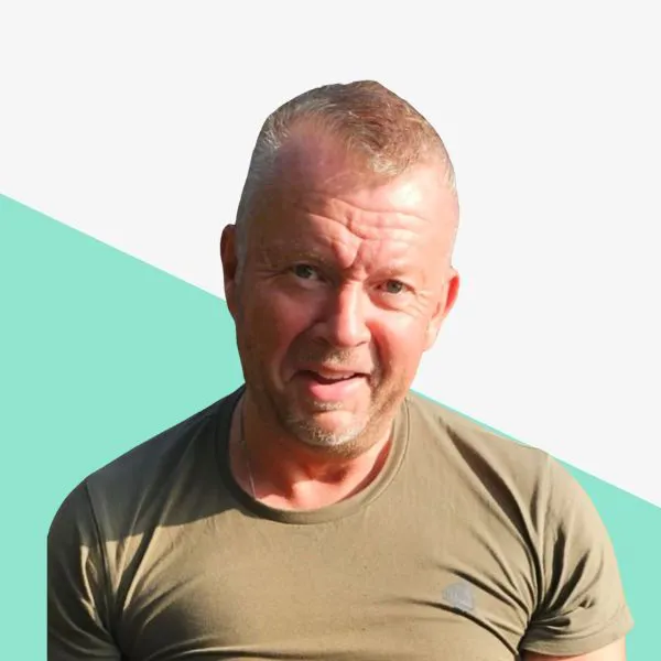 Smiling man in a green shirt against a light background.