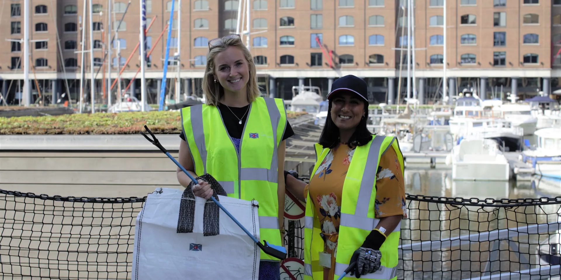 Two Clarksons employees in florescent jackets picking up litter
