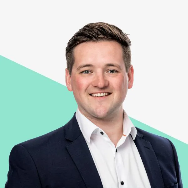 Smiling man in a suit against a minimalist background.