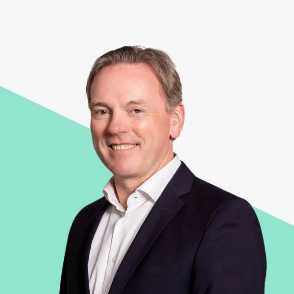 Smiling man in a suit against a minimal background.