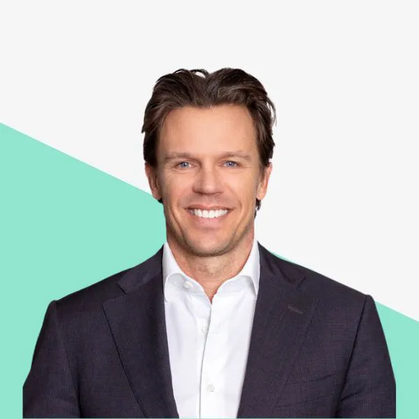 Smiling man in a suit against a geometric background.