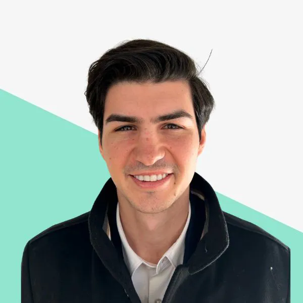 Smiling young man in a black jacket, green background.