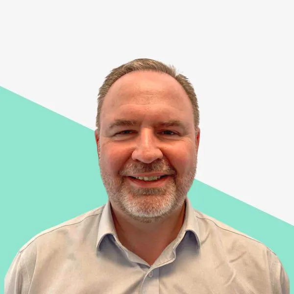 Smiling man with a beard on a gradient background.