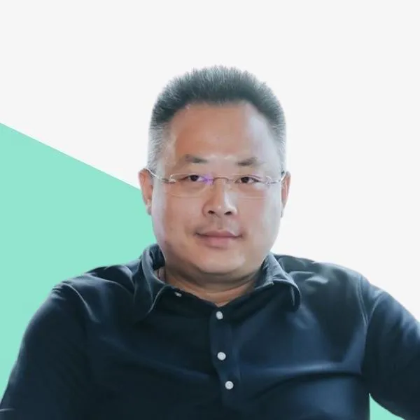 Man in a black shirt with glasses, neutral background.