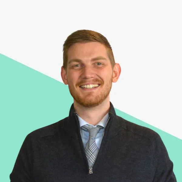 Smiling man in a dark sweater and tie.