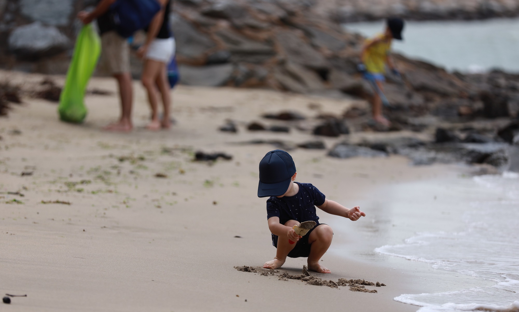 little boy playing with sand on a beach