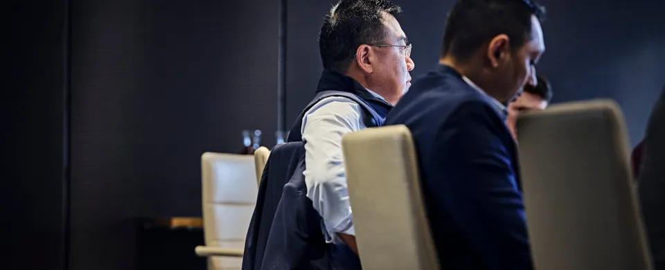 man in meeting, dark room, sitting in chair