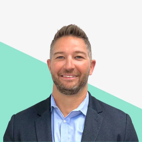 Man in a suit smiling against a light background.