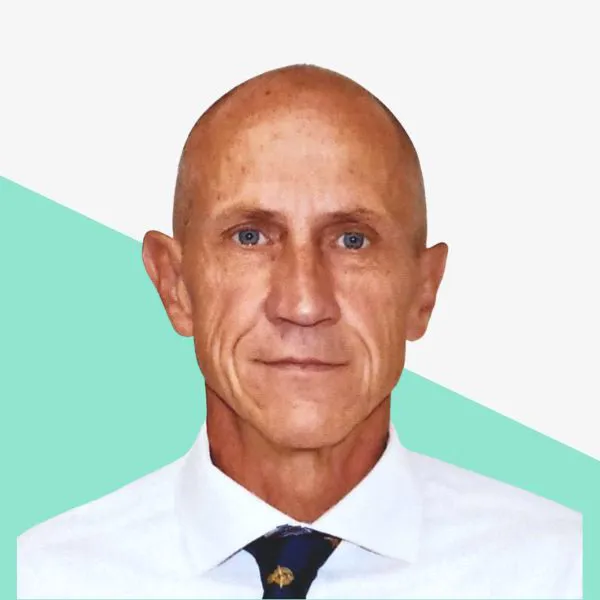 Bald man in a white shirt and tie, neutral background.